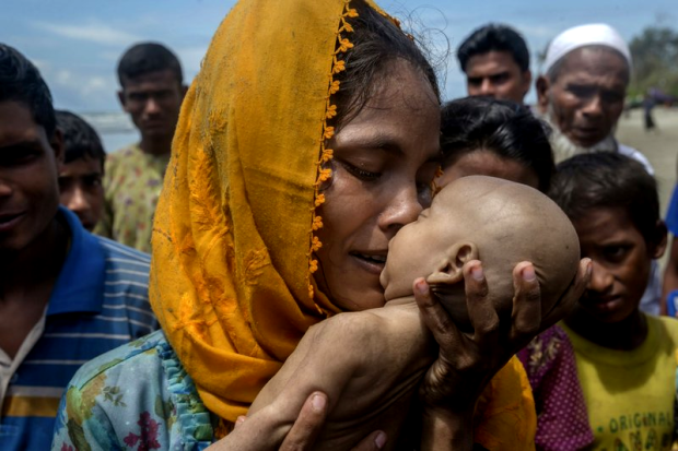 A Rohingya Muslim woman Hanida Begum, who crossed over from Myanmar into Bangladesh, kisses her infant son Abdul Masood who died when the boat they were traveling in capsized just before reaching the shore of the Bay of Bengal, in Shah Porir Dwip, Bangladesh, Thursday, Sept. 14, 2017. Nearly three weeks into a mass exodus of Rohingya fleeing violence in Myanmar, thousands were still flooding across the border Thursday in search of help and safety in teeming refugee settlements in Bangladesh. (AP Photo/Dar Yasin)